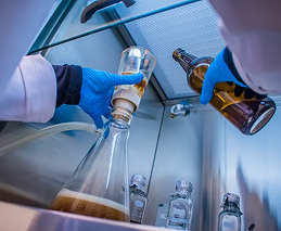 Ensaio laboratorial com profissional realizando análises de bebidas em recipientes de vidro